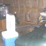 Guttered make-shift living room. Ice chest used as refrigerator.